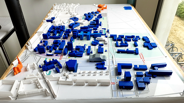 Architekturmodell des KIT-Campus mit blau-wei&szlig;en Geb&auml;udevolumen auf einer Grundrisszeichnung.