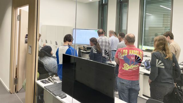 Gruppe von Menschen in einem Elektronikbüro und interagieren mit unterschiedlichen Geräten.