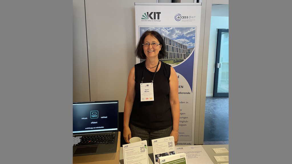 Das Foto zeigt Karin Muller vor einem Informationsbanner des KIT (Karlsruher Institut für Technologie).